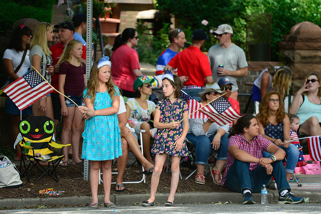 DENVER, CO - JULY 4: Parade spectators wave American flags as a float goes by during the seventh an...