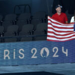 NANTERRE, FRANCE - JULY 27: Fans display a national flag of United States as branding is seen on an advertising board on day one of the Olympic Games Paris 2024 at Paris La Defense Arena on July 27, 2024 in Nanterre, France. (Photo by Arturo Holmes/Getty Images)