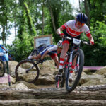 ELANCOURT, FRANCE - JULY 28: Loana Lecomte of Team France (obscured) crashes (L) while Laura Stigger of Team Austria (R) competes during the Women’s Cross-Country Cycling Mountain Bike Gold Medal race on day two of the Olympic Games Paris 2024 at Elancourt Hill on July 28, 2024 in Elancourt, France. (Photo by Alex Broadway/Getty Images)