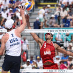 PARIS, FRANCE - JULY 30: Andrew Benesh of Team United States attacks the net against the block attempt by Zouheir Elgraoui of Team Morocco during the Men's Preliminary Phase - Pool D match on day four of the Olympic Games Paris 2024 at Eiffel Tower Stadium on July 30, 2024 in Paris, France. (Photo by Lintao Zhang/Getty Images)