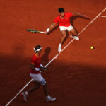 PARIS, FRANCE - JULY 30: Carlos Alcaraz of Team Spain plays a forehand shot as partner Rafael Nadal of Team Spain looks on against Tallon Griekspoor of Team Netherlands and Wesley Koolhof of Team Netherlands during the Men's Doubles second round match on day four of the Olympic Games Paris 2024 at Roland Garros on July 30, 2024 in Paris, France. (Photo by Clive Brunskill/Getty Images)