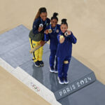 PARIS, FRANCE - AUGUST 01: (EDITORS NOTE: Image was captured using a robotic camera positioned above the field of play) Gold medalist Simone Biles of Team United States (C), Silver medalist Rebeca Andrade of Team Brazil (L) and Bronze medalist Sunisa Lee of Team United States (R) pose for a selfie during the Artistic Gymnastics Women's All-Around Final medal ceremony on day six of the Olympic Games Paris 2024 at Bercy Arena on August 01, 2024 in Paris, France. (Photo by Dan Mullan/Getty Images)