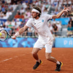 PARIS, FRANCE - AUGUST 01: Stefanos Tsitsipas of Team Greece plays a backhand against Novak Djokovic of Team Serbia during the Men's Singles Quarter-final match on day six of the Olympic Games Paris 2024 at Roland Garros on August 01, 2024 in Paris, France. (Photo by Matthew Stockman/Getty Images)