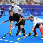 PARIS, FRANCE - AUGUST 02: Mathias Mueller of Team Germany controls the ball whilst under pressure from Samuel Ward and Rupert Shipperley of Team Great Britain during the Men's Pool A match between Great Britain and Germany on day seven of the Olympic Games Paris 2024 at Stade Yves Du Manoir on August 02, 2024 in Paris, France. (Photo by Buda Mendes/Getty Images)