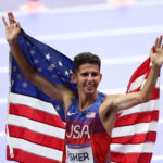 PARIS, FRANCE - AUGUST 02: Bronze medalist Grant Fisher of Team United States celebrates after the Men's 10,000m Final on day seven of the Olympic Games Paris 2024 at Stade de France on August 02, 2024 in Paris, France. (Photo by Steph Chambers/Getty Images)