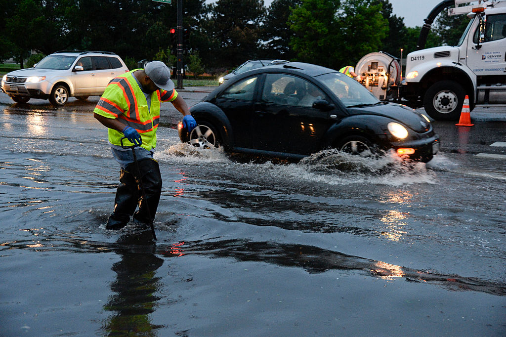 DENVER, CO - JUNE 24: Denver Public Works workers try to unclog the storm drain at 23rd and Colorad...