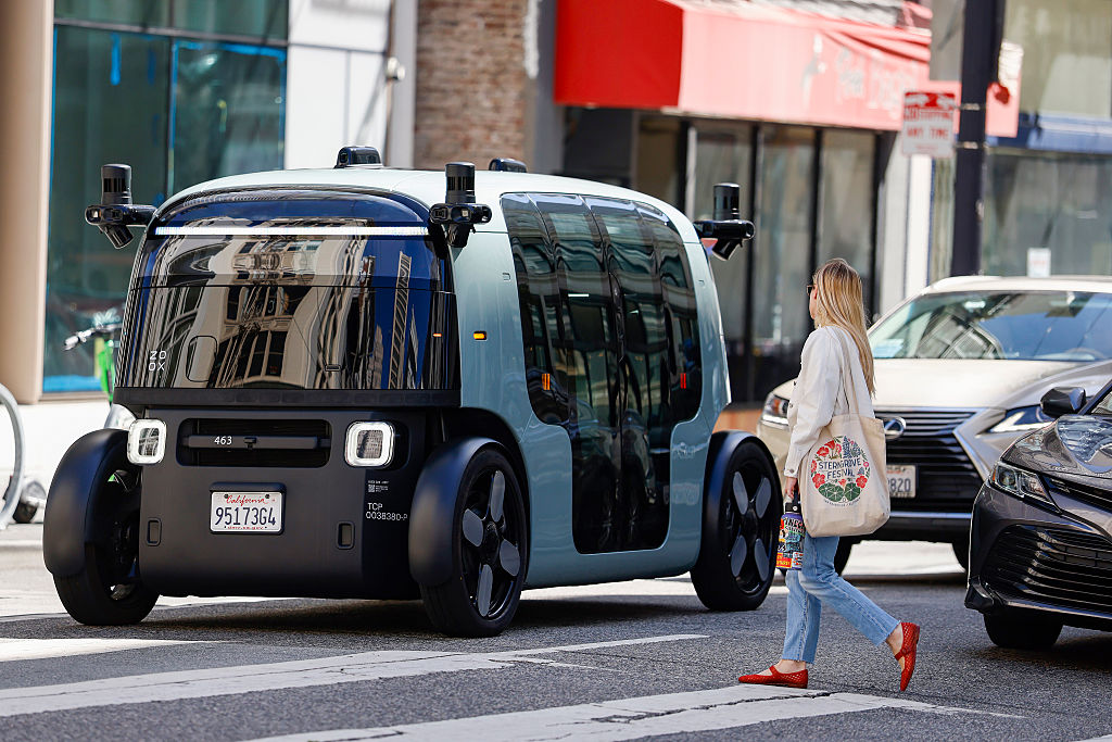 SAN FRANCISCO, CALIFORNIA - AUGUST 03: A pedestrian crosses in front of an Amazon-owned Zoox driver...